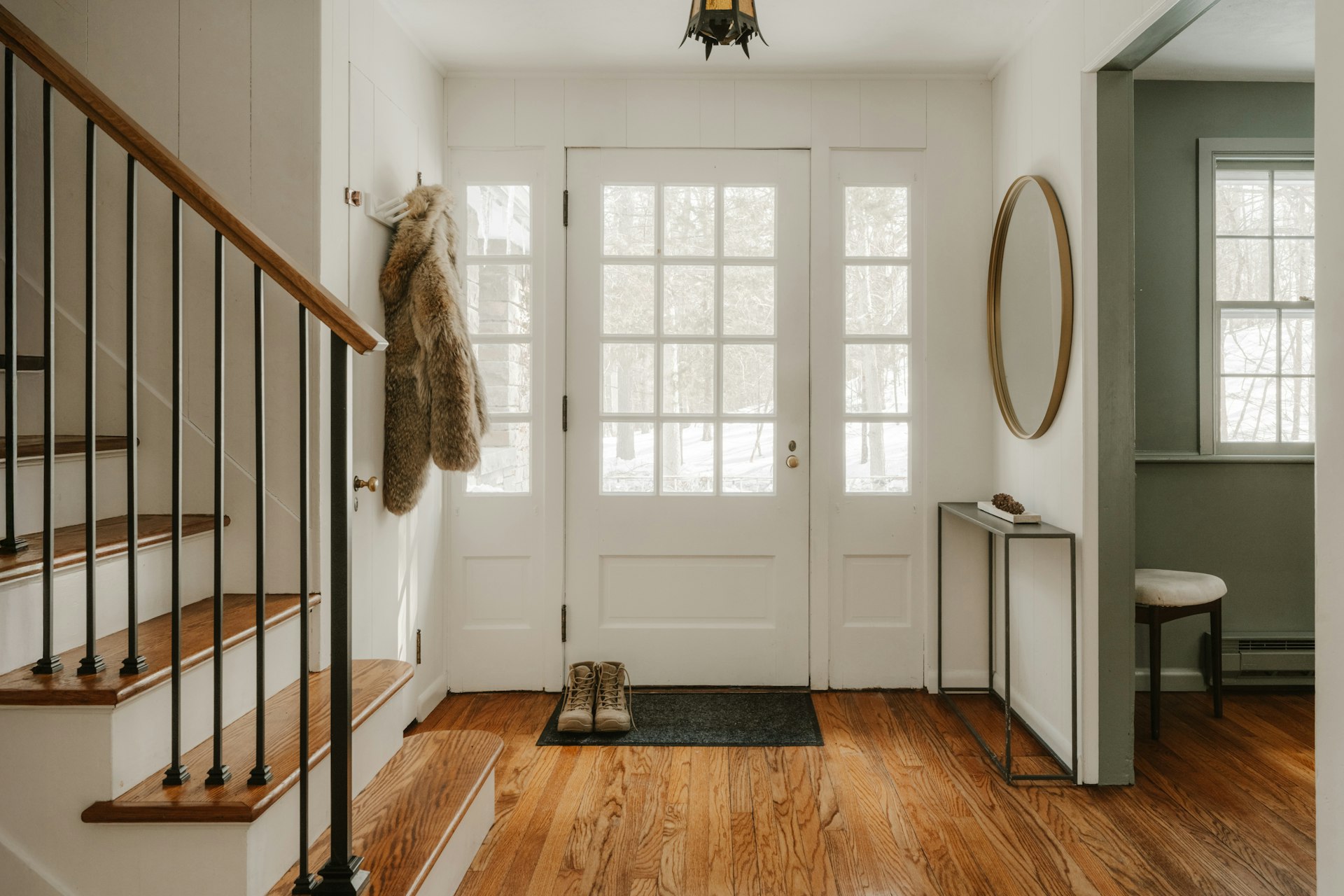 A warm, sunlit entryway with wooden floors and a glass-paned front door.